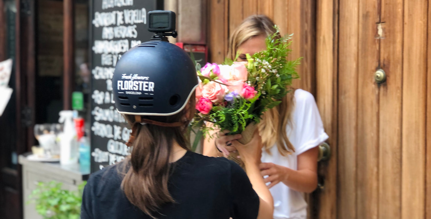 Elena Zhabreva florista y mensajera de Florster entregando un ramo de flores en una calle de Barcelona