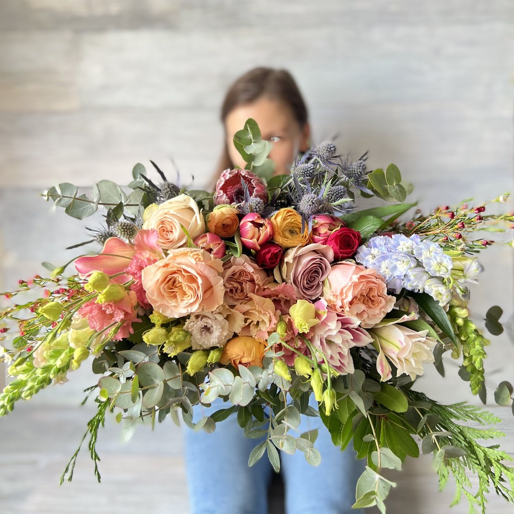 Ramo variado de florster con vista de perfil con tulipanes, proteas, ranúnculos y eucalipto.