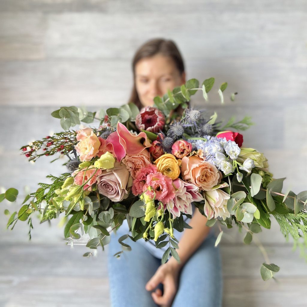 Ramo de flores variado colorido de perfil con rosas, proteas, eucalipto, lisiantus y ranúnculo.,