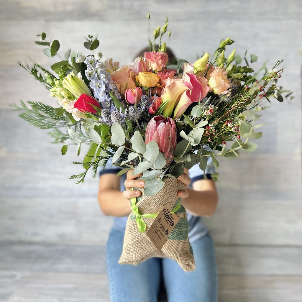 Ramo de flores de tamaño mediano con proteas, rosas, calas, tulipanes, lisianthis, lilium, ranunculos y eucalipto.