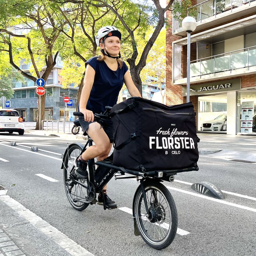 Mensajera de Florster en bicicleta de carga con mochila de flores en Barcelona